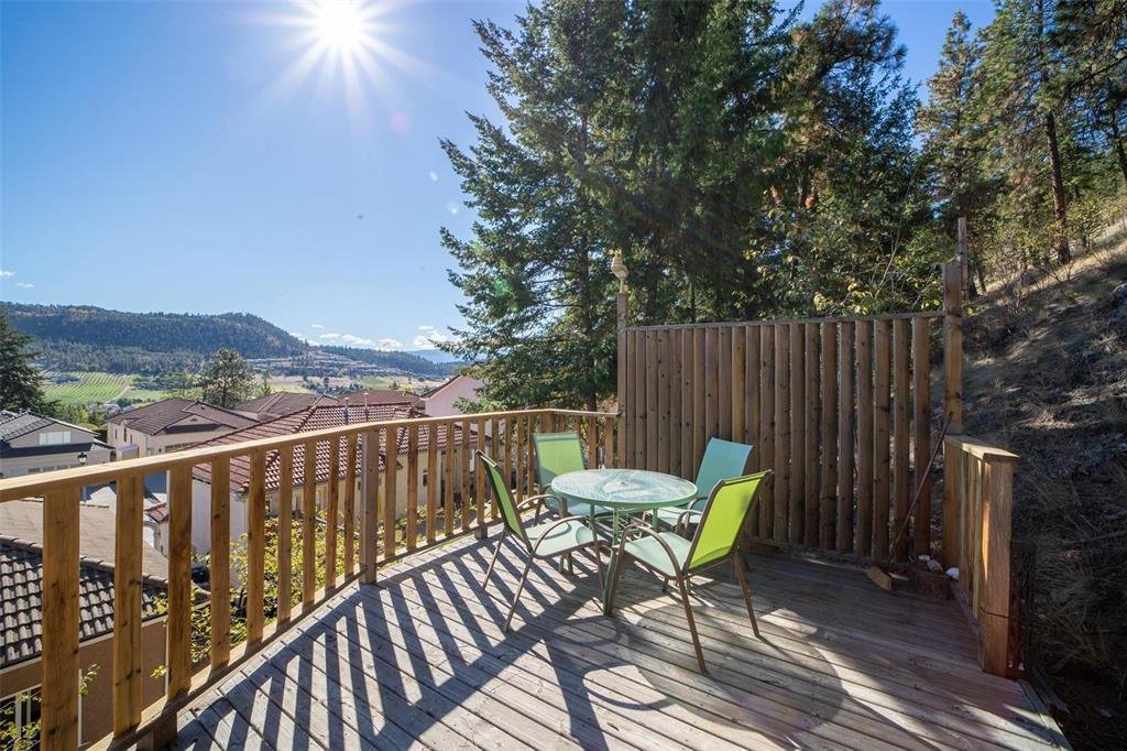 A wooden deck with a table and chairs overlooking a valley.